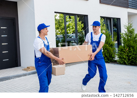 Two removal company workers are loading boxes into a minibus. Two removal company workers are loading boxes into a minibus. 142712656