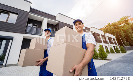 Two removal company workers unloading boxes into new customer's home 142712758