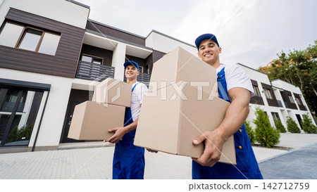 Two removal company workers unloading boxes into new customer's home Two removal company workers unloading boxes into new customer's home 142712759