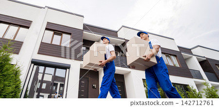 Two removal company workers unloading boxes into new customer's home 142712761