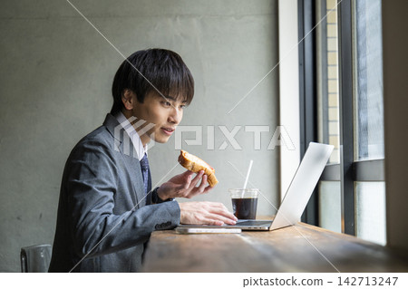 A businessman working while eating toast at a cafe. A businessman working while eating toast at a cafe. 142713247