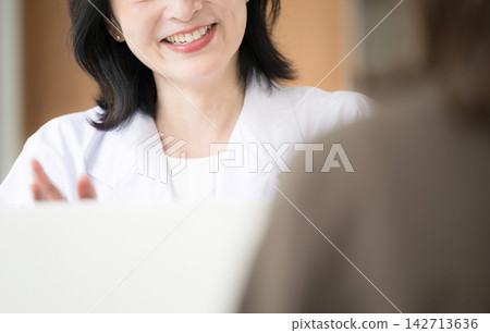 A female doctor faces patients and provides medical counseling, examinations, and health consultations with a smile; only her mouth and hands are visible, without a face. A female doctor faces patients and provides medical counseling, examinations, and health consultations with a smile; only her mouth and hands are visible, without a face. 142713636