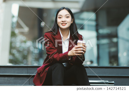 Focused woman in blazer types on laptop outdoors. Urban professional works remotely on stairs. She uses modern tech for business and connection. Focused woman in blazer types on laptop outdoors. Urban professional works remotely on stairs. She uses modern tech for business and connection. 142714521