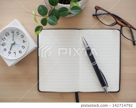 一張俯拍照片顯示,一張木桌上放著筆記本、鋼筆、眼鏡和手錶。 一張俯拍照片顯示,一張木桌上放著筆記本、鋼筆、眼鏡和手錶。 142714792