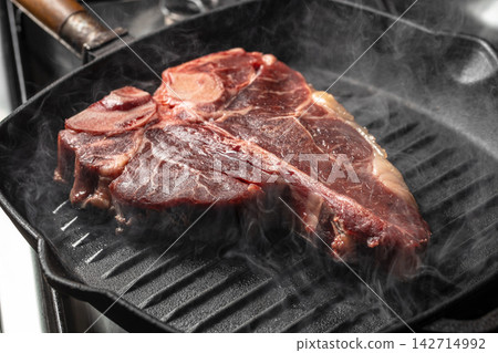 Raw T Bone Steak Searing in Smoking Grill Pan Raw T Bone Steak Searing in Smoking Grill Pan 142714992
