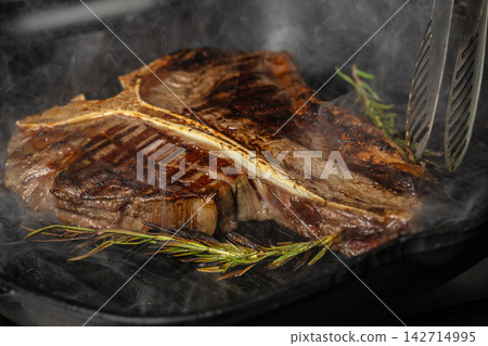 Chef Grilling T Bone Steak with Rosemary and Tongs 142714995