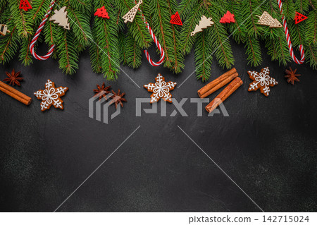 Festive Christmas decorations with pine branches, gingerbread cookies, cinnamon sticks, and star anise on a dark background for holiday-themed designs and celebrations Festive Christmas decorations with pine branches, gingerbread cookies, cinnamon sticks, and star anise on a dark background for holiday-themed designs and celebrations 142715024