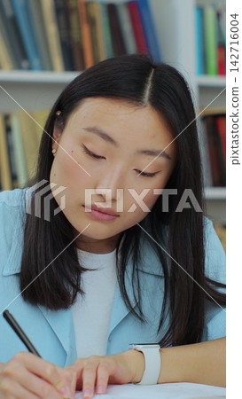 Student collecting information from different books, Asian girl in blue shirt gathering data for the paper. Self education concept. 142716004