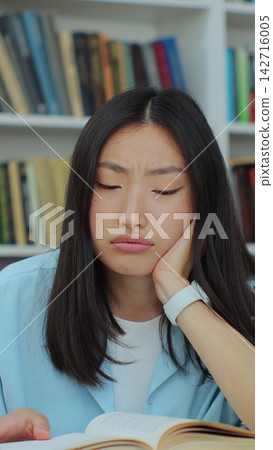 Student collecting information from different books, Asian girl in blue shirt gathering data for the paper. Self education concept. Student collecting information from different books, Asian girl in blue shirt gathering data for the paper. Self education concept. 142716005