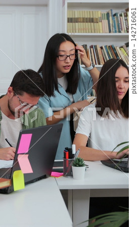 Students have discussion, use laptop, prepare for exams together, helping, researching subjects for the paper assignment. University library. Students have discussion, use laptop, prepare for exams together, helping, researching subjects for the paper assignment. University library. 142716061