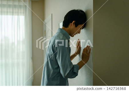 一名男子用頭猛撞牆壁,臉上露出痛苦的表情。 一名男子用頭猛撞牆壁,臉上露出痛苦的表情。 142716368
