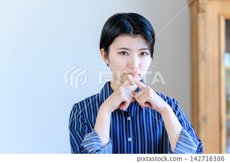 一名女子用手指比劃出一個「X」型 一名女子用手指比劃出一個「X」型 142716386