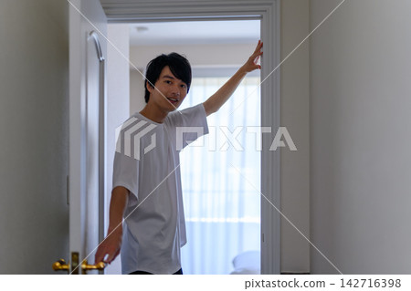 一個男人打開門，探出頭來。 142716398