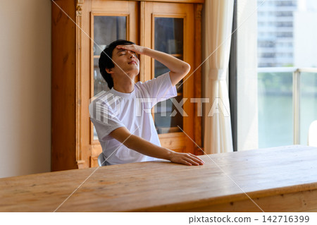The man places his hand on his forehead to check his temperature. The man places his hand on his forehead to check his temperature. 142716399
