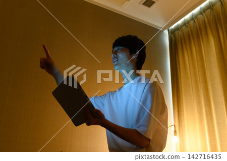 一名男子一邊看著平板電腦一邊指著什麼。 一名男子一邊看著平板電腦一邊指著什麼。 142716435