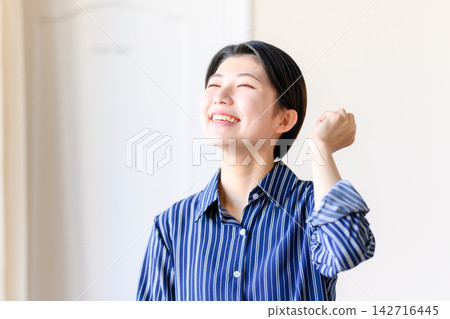 一位女士揮拳慶祝，臉上露出成就感和笑容。 142716445