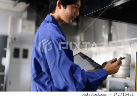 A worker checking documents in the kitchen A worker checking documents in the kitchen 142716451