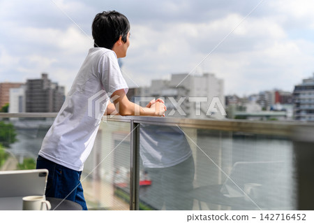 A man looking out at the cityscape from his balcony. A man looking out at the cityscape from his balcony. 142716452