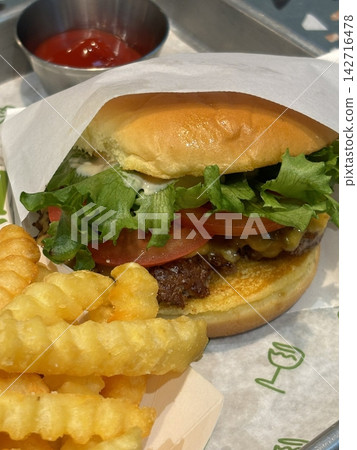 A classic combination of a juicy burger with fresh toppings served alongside golden, crispy French fries. Perfect for a satisfying meal that blends savory flavors and crunchy textures. 142716478