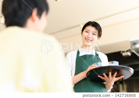 一位微笑的女服務生端著托盤 一位微笑的女服務生端著托盤 142716808