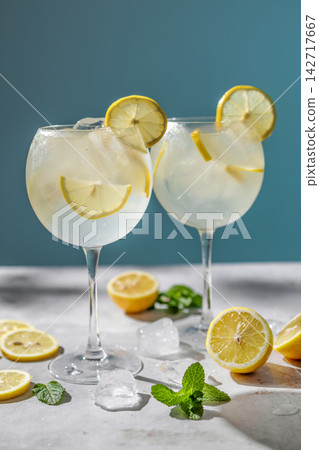 Limoncello Spritz Cocktails in Wine Glasses with Lemon, Ice and Mint on Blue Background Limoncello Spritz Cocktails in Wine Glasses with Lemon, Ice and Mint on Blue Background 142717667