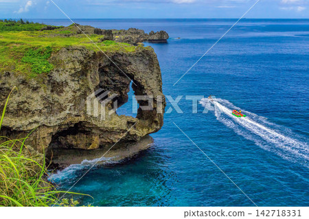 The sheer cliffs of Manzamo and a banana boat sailing offshore. The sheer cliffs of Manzamo and a banana boat sailing offshore. 142718331