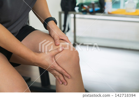 Woman holding painful knee after workout at gym 142718394