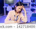 Stressed young Asian office worker overwhelmed by paperwork while working on a laptop. 142718400