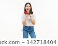 Happy Asian woman holding credit cards with a confident smile isolated on white studio background. 142718404