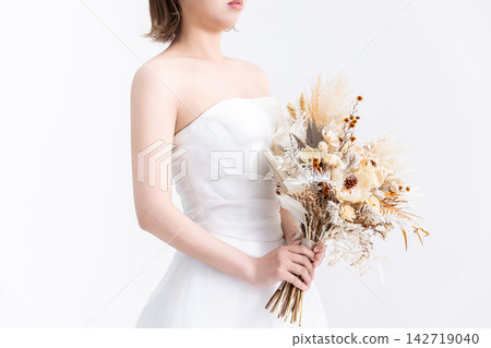 身穿婚紗的女子手捧一束花。 身穿婚紗的女子手捧一束花。 142719040