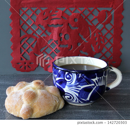 Mexican sweet bread with coffee in a talavera cup, pan de muerto, papel picado and traditional Mexican skulls Mexican sweet bread with coffee in a talavera cup, pan de muerto, papel picado and traditional Mexican skulls 142720303