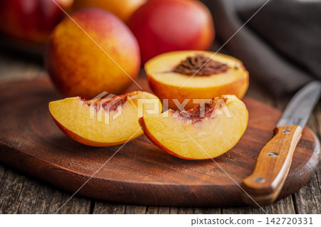 Sliced Ripe nectarine Peaches on Wooden Cutting Board With Knife Ready to Serve Sliced Ripe nectarine Peaches on Wooden Cutting Board With Knife Ready to Serve 142720331