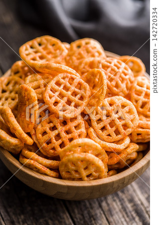 Closeup Bowl Of Spicy Waffle Potato Chips Snack In Wooden Bowl Rustic Background Closeup Bowl Of Spicy Waffle Potato Chips Snack In Wooden Bowl Rustic Background 142720334