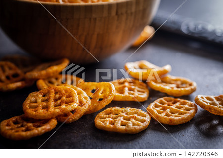 Close-Up Of Seasoned Waffle Potato Chips Scattered Next To A Wooden Bowl Snack Food Close-Up Of Seasoned Waffle Potato Chips Scattered Next To A Wooden Bowl Snack Food 142720346