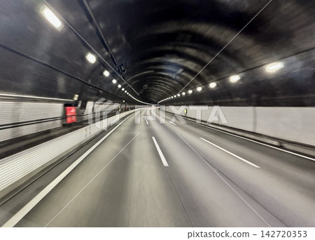 A road scene of driving through a highway tunnel lined with lights. A road scene of driving through a highway tunnel lined with lights. 142720353