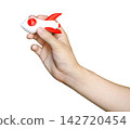 Human hand holding a white and red toy rocket model against. Business startup, innovation, and growth mission concept. Minimalist studio shot for success and ambition. 142720454