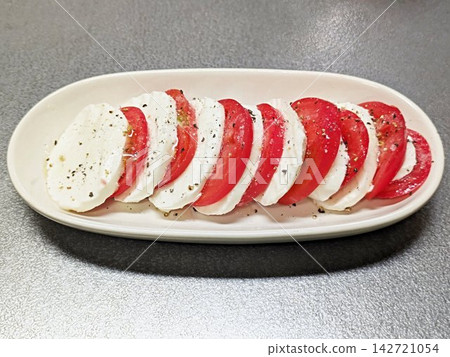 A close-up of Caprese salad, an Italian appetizer, made with layers of thinly sliced tomatoes and mozzarella cheese. A close-up of Caprese salad, an Italian appetizer, made with layers of thinly sliced tomatoes and mozzarella cheese. 142721054