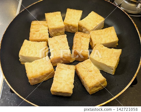A close-up of sliced deep-fried tofu being pan-fried until the surface is golden brown and fragrant. A close-up of sliced deep-fried tofu being pan-fried until the surface is golden brown and fragrant. 142721058