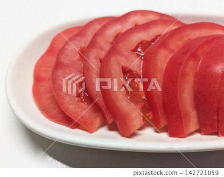 A close-up of fresh sliced tomatoes neatly arranged on a white plate. A close-up of fresh sliced tomatoes neatly arranged on a white plate. 142721059