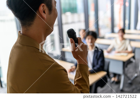 一位手持麥克風的男教師和學生們 142721522