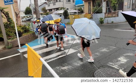 下雨天,小學生穿過居民區步行上學。 下雨天,小學生穿過居民區步行上學。 142722530