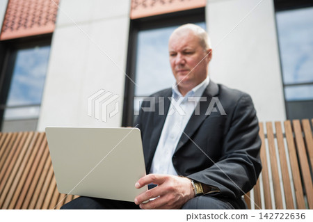 Businessman working on laptop outdoors Businessman working on laptop outdoors 142722636