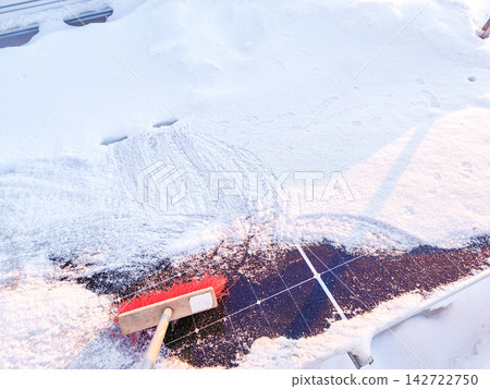 Cleaning snow off solar panels with broom brush. House roof Cleaning snow off solar panels with broom brush. House roof 142722750