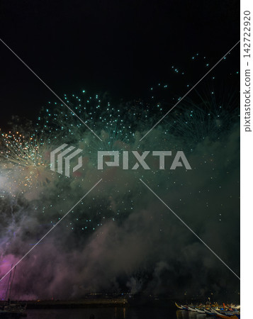 Bright fireworks display over water in night sky Bright fireworks display over water in night sky 142722920
