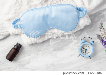 Blue sleep mask with alarm clock and essential oil bottle on white marble background, Good night sleep concept Blue sleep mask with alarm clock and essential oil bottle on white marble background, Good night sleep concept 142724863