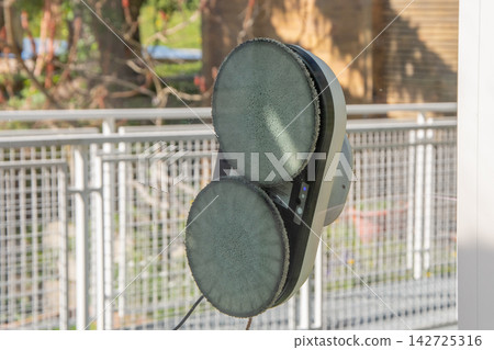 Robotic window cleaning device attached to glass outdoors 142725316