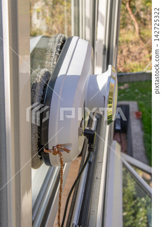 Automated window cleaning robot attached to glass pane on sunny day Automated window cleaning robot attached to glass pane on sunny day 142725322