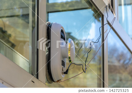 Robotic window cleaner attached to glass pane on sunny day Robotic window cleaner attached to glass pane on sunny day 142725325