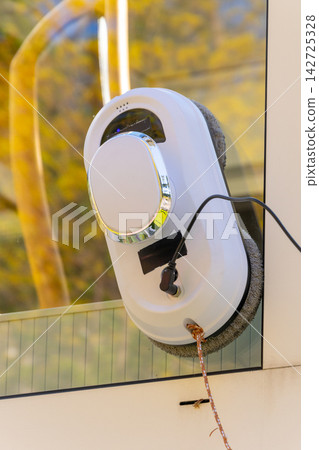 Robot window cleaner attached to glass surface outdoors Robot window cleaner attached to glass surface outdoors 142725328