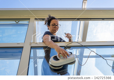 Woman cleaning a skylight with electric window cleaner from above Woman cleaning a skylight with electric window cleaner from above 142725366